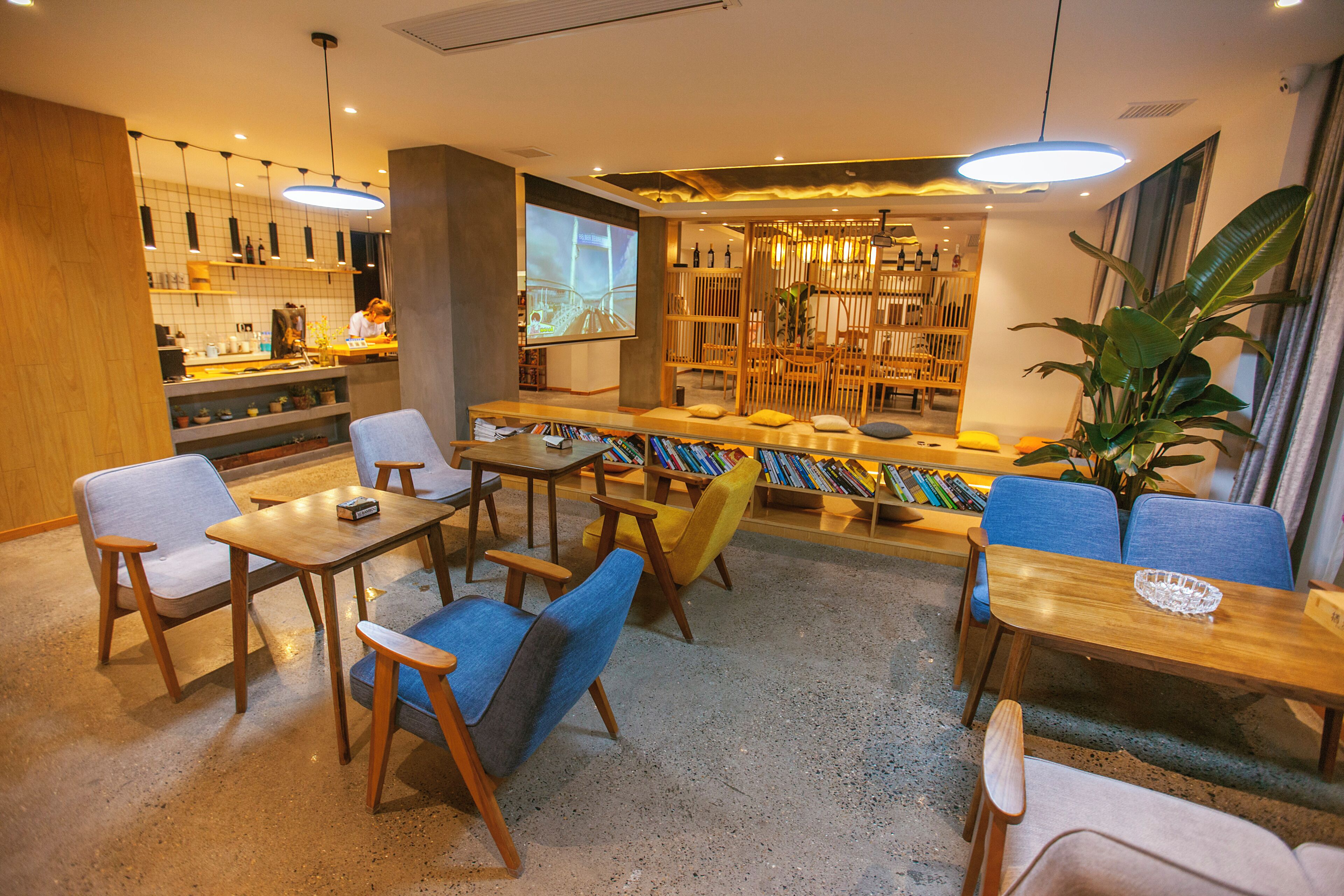 Un interior moderno con disposición de asientos, una zona de bar y una pantalla de proyección.