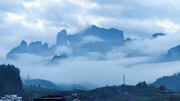 A mountainous landscape with a prominent peak, surrounded by clouds and vegetation.