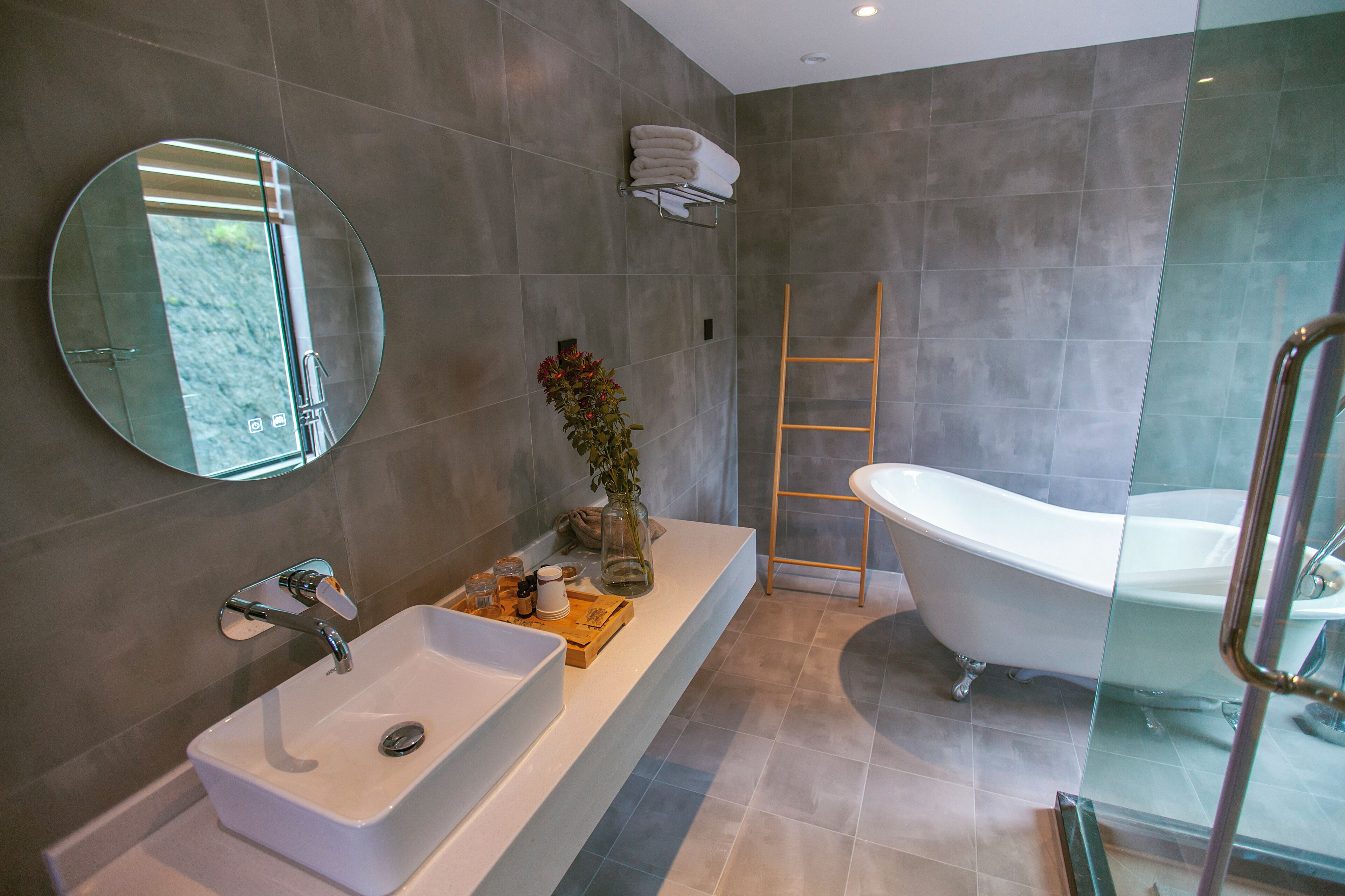 Une salle de bain moderne avec une baignoire sur pieds, un grand miroir et une cabine de douche en verre.