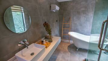 Une salle de bain moderne avec une baignoire sur pieds, un grand miroir et une cabine de douche en verre.