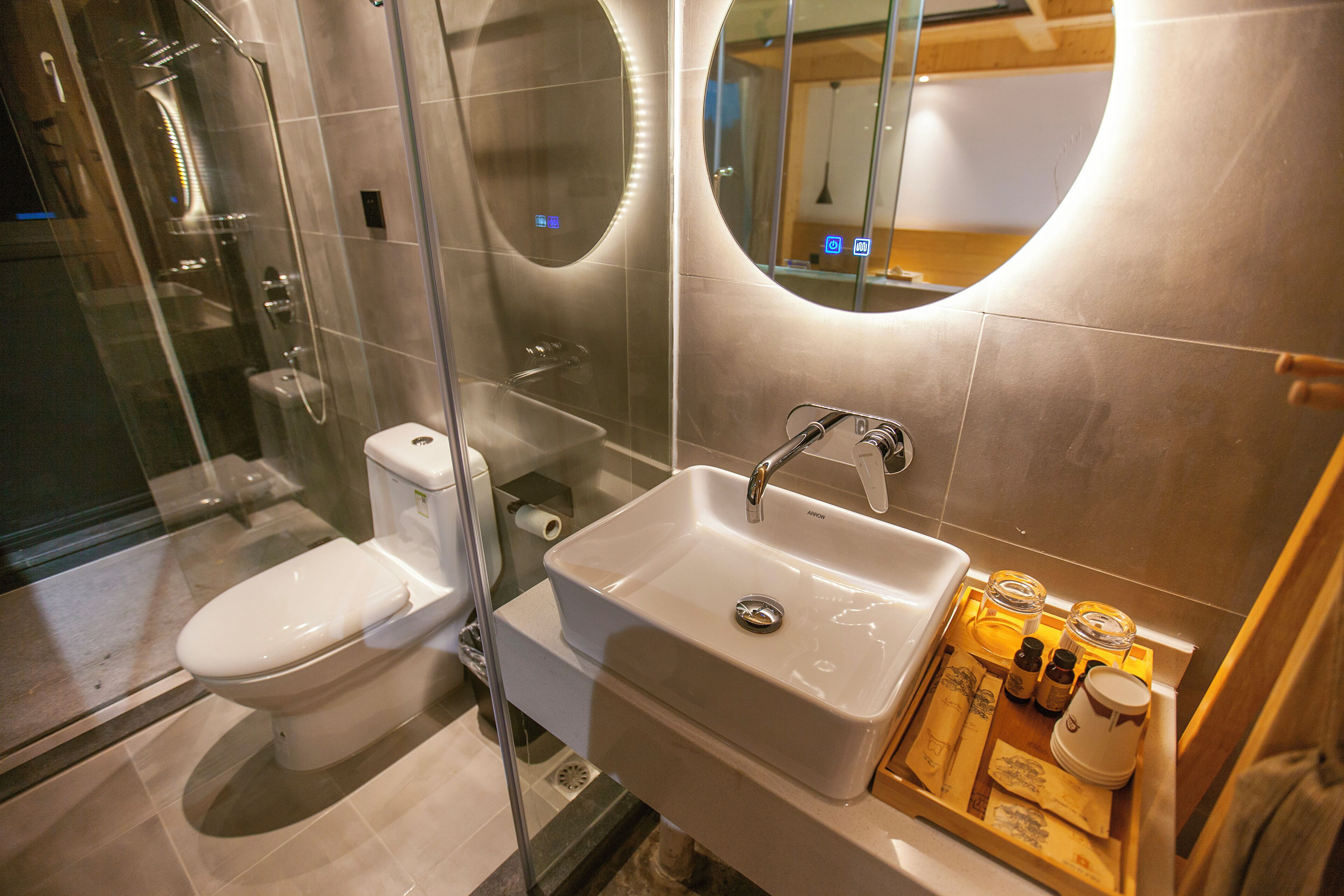 Une salle de bain moderne avec une douche à parois de verre, des toilettes blanches et un lavabo équipé de produits de toilette.