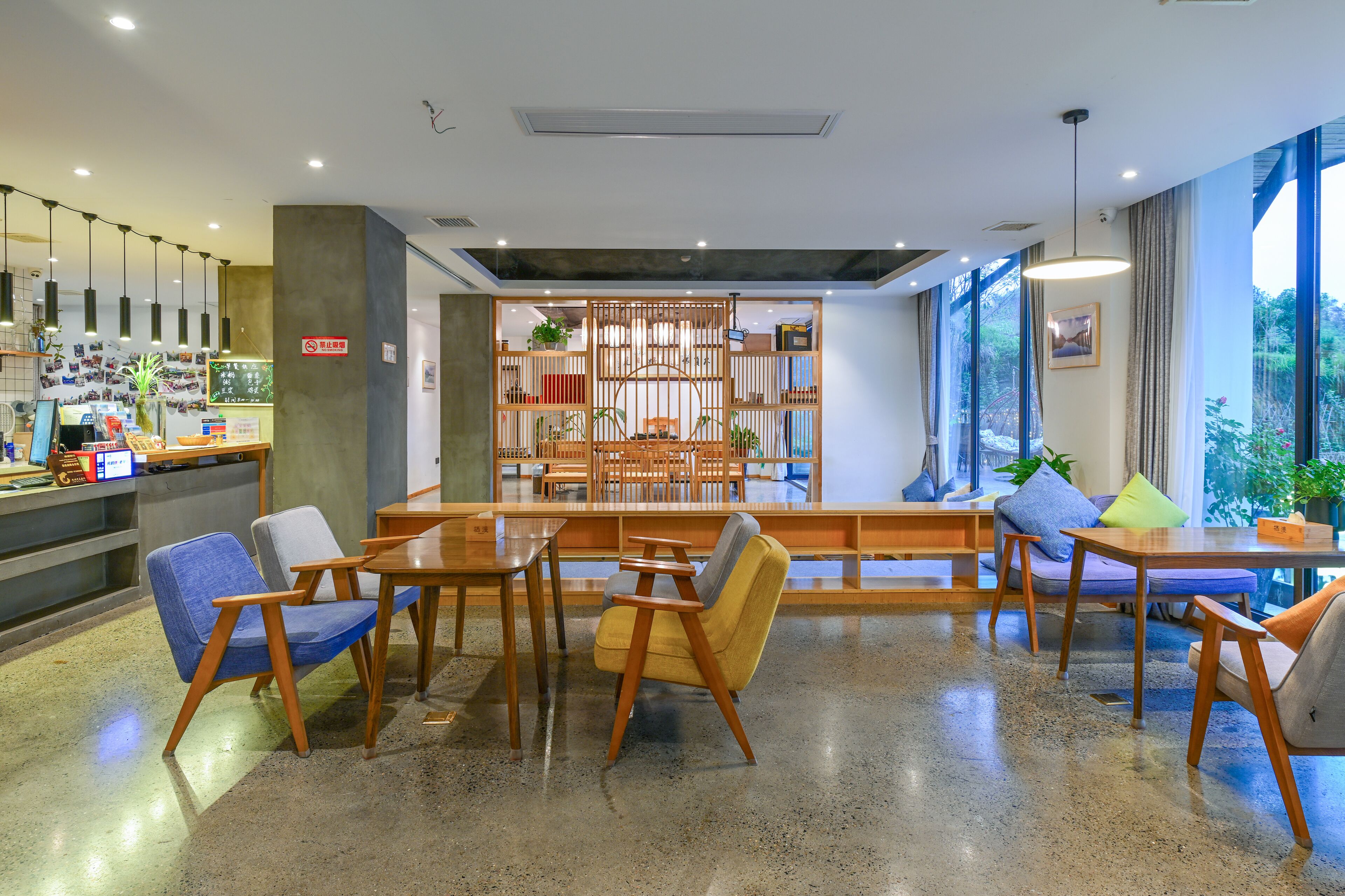 A modern lobby with seating areas, a reception desk, and a bookshelf.