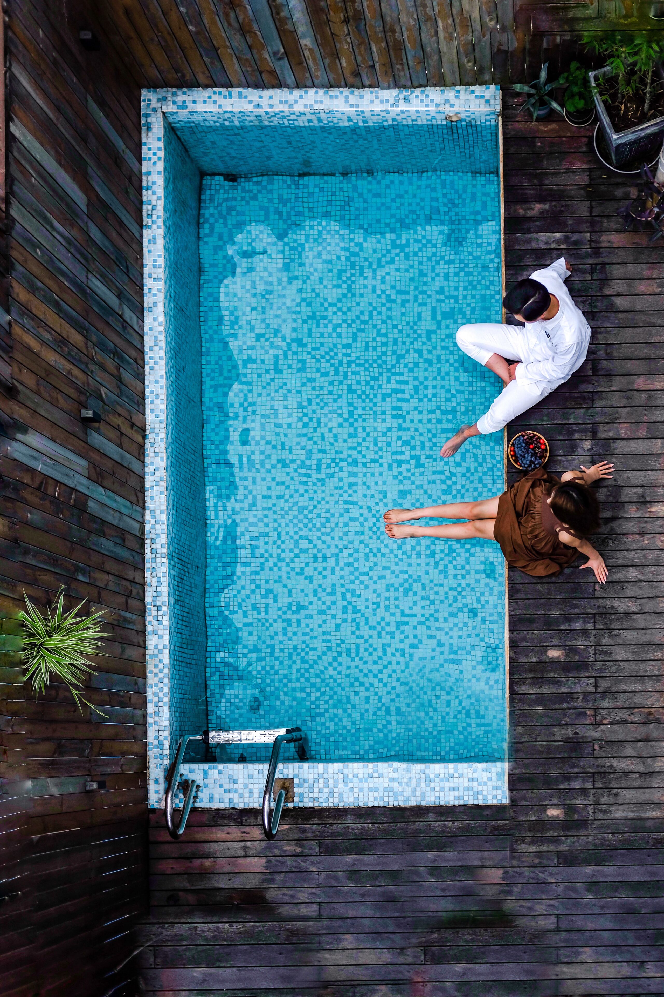 Vista aérea de una piscina rectangular con borde de azulejos, rodeada por una terraza de madera.