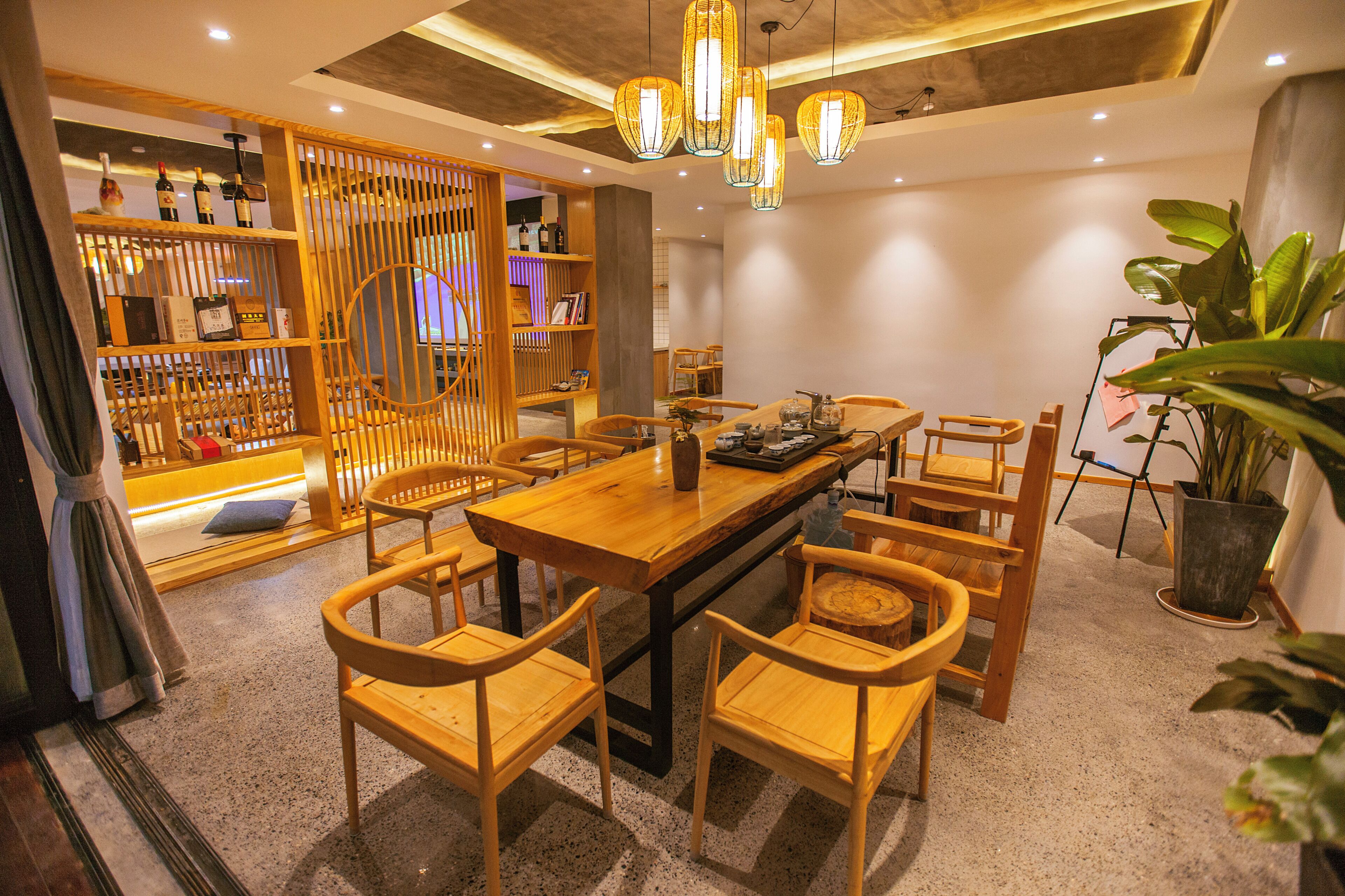 A dining area with a wooden table and chairs, a decorative light fixture, and a plant.
