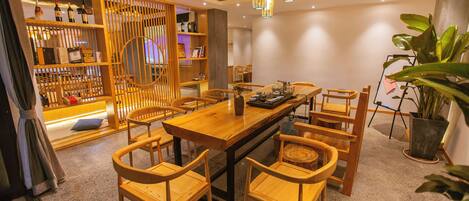 A dining area with a wooden table and chairs, a decorative light fixture, and a plant.