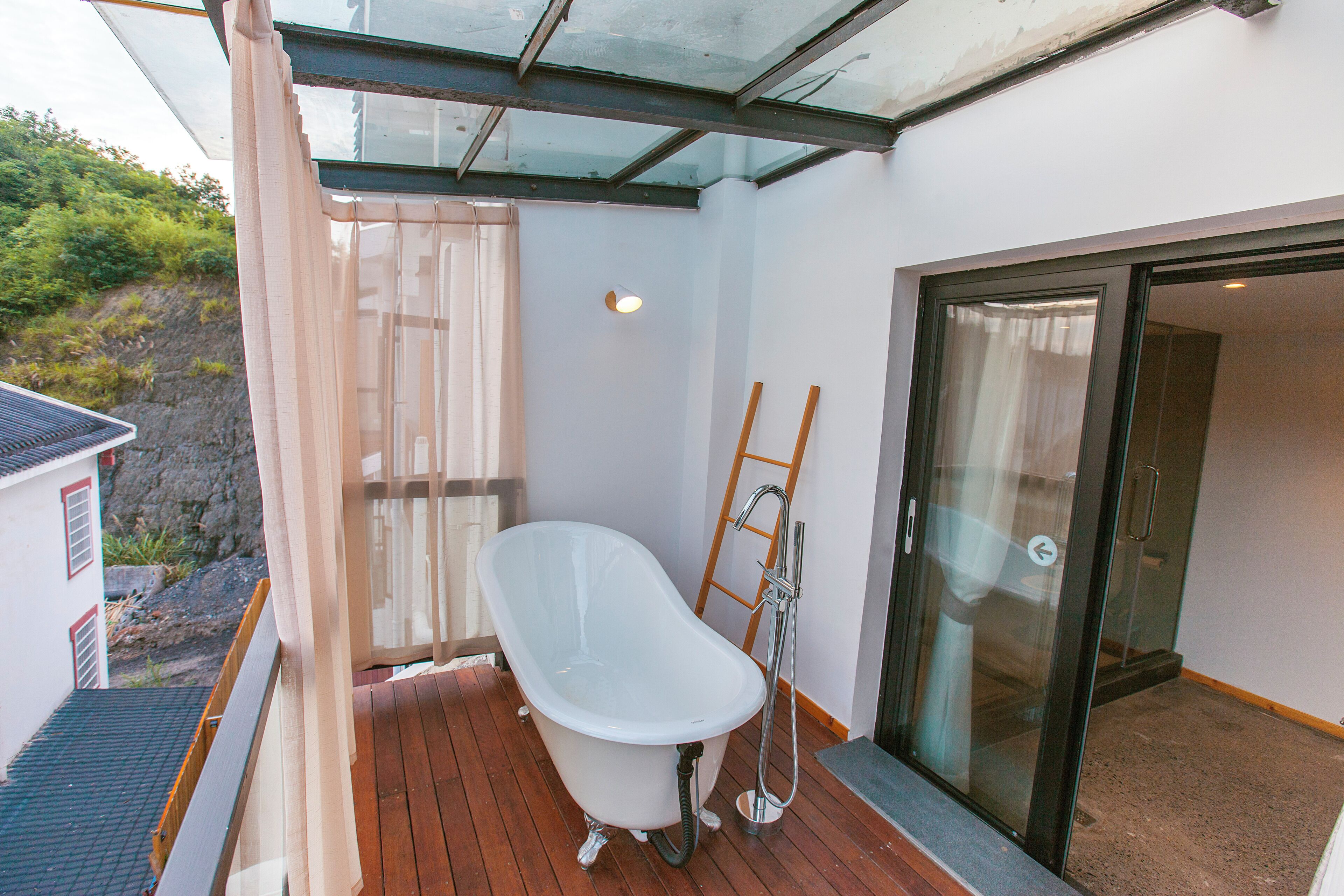 A modern bathroom with a freestanding bathtub, a glass shower enclosure, and a wooden ladder.