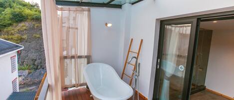 A modern bathroom with a freestanding bathtub, a glass shower enclosure, and a wooden ladder.