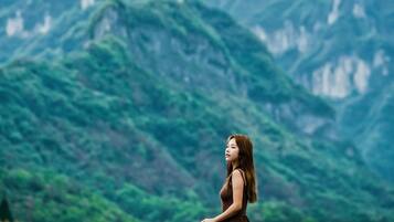 A person sitting on a roof overlooking a mountainous landscape.
