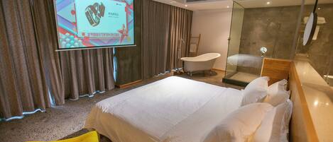 A hotel room with a large bed, a bathtub, a shower, and a yellow chair.