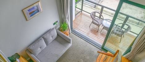 A balcony with a sofa, a dining table, and chairs, and a view of the outside.