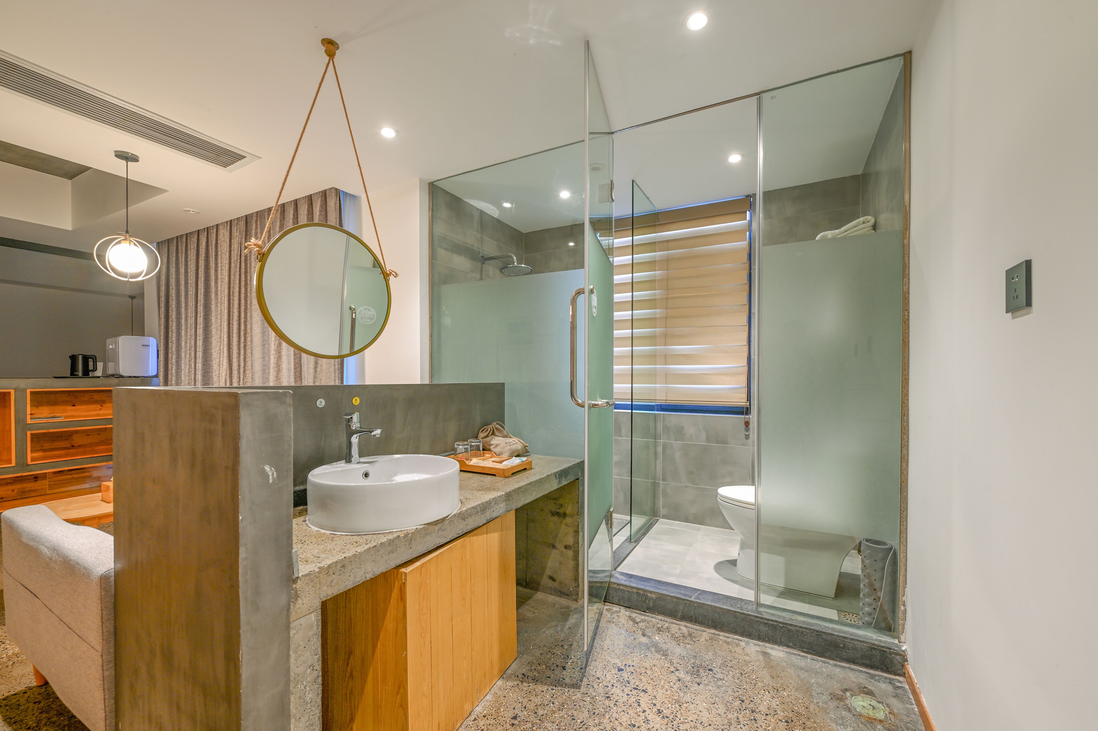 A modern bathroom with a glass-enclosed shower, a round mirror, and a wooden vanity.