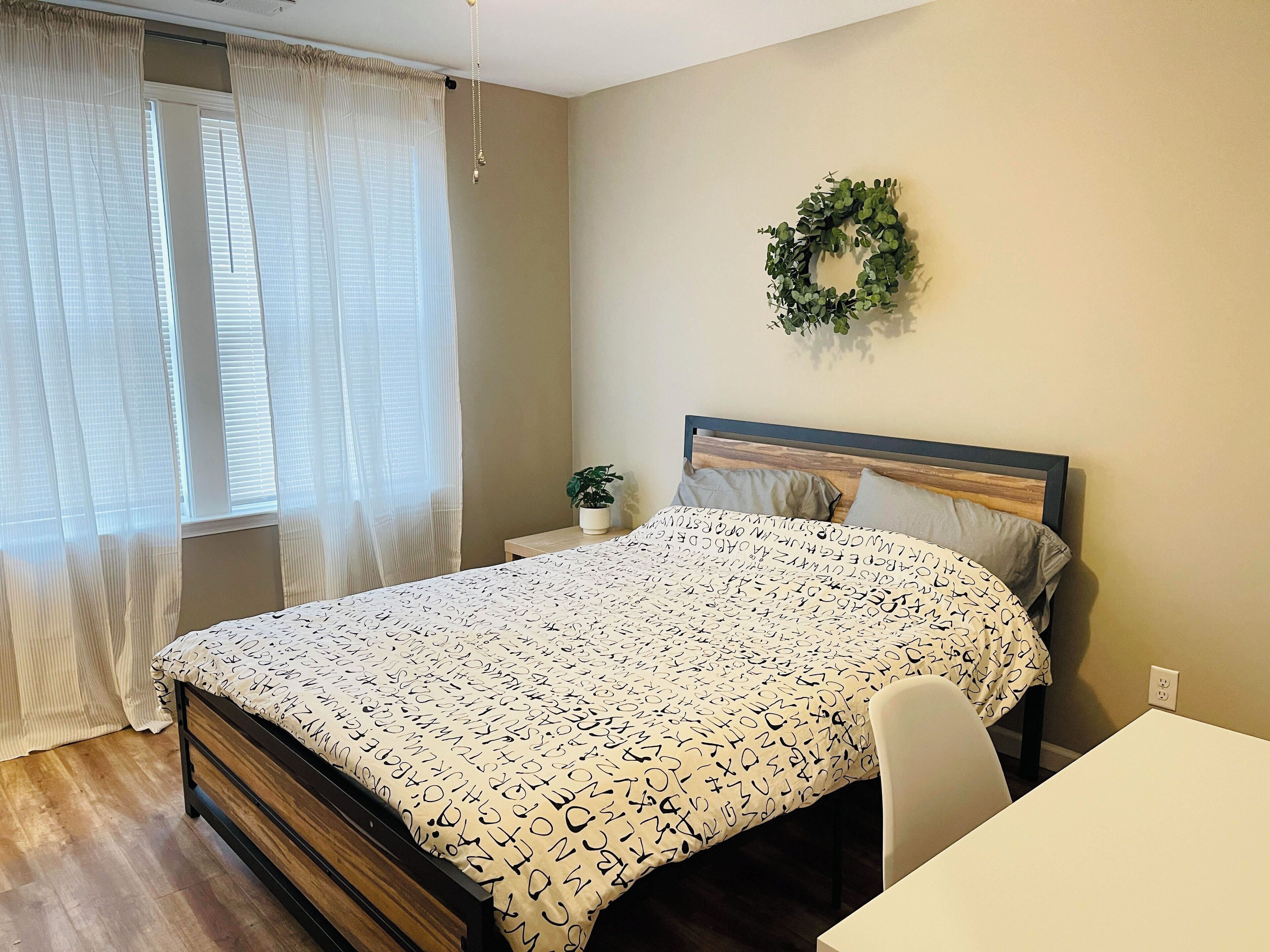 Ein Schlafzimmer mit einem Bett, einem Nachttisch, einer Topfpflanze und einem Wandkranz.