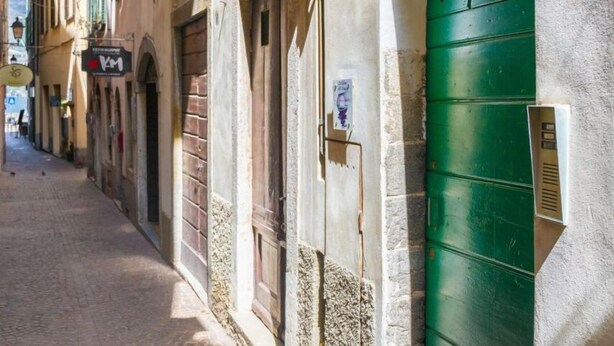 Een smalle straat met gebouwen en boogvormige deuropeningen, inclusief een groene deur.