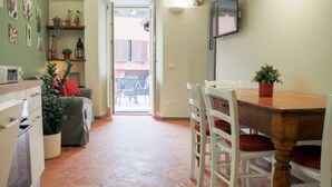 Een kleine keuken met een eethoek, een aan de muur bevestigde televisie en uitzicht door een geopende deur.