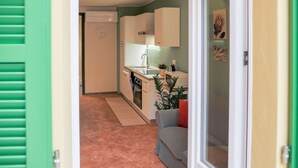 Een compacte keuken met witte kastjes, een spoelbak en een klein aanrecht.