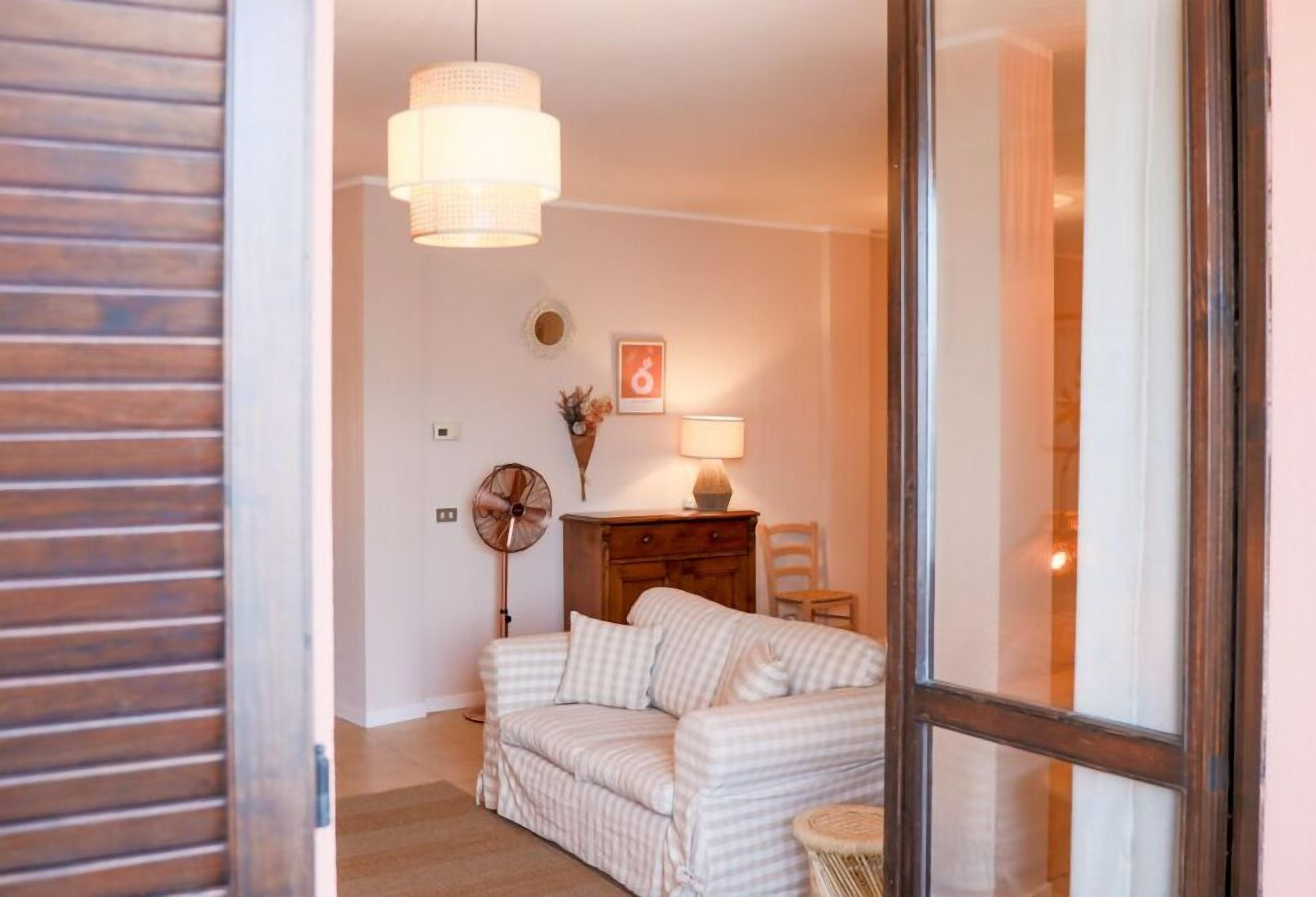 A cozy room with a checkered sofa, a wooden cabinet, a fan, and a lamp.
