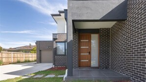 A modern house with a brick exterior, a wooden door, and a garage.