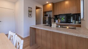 A modern kitchen with wooden cabinets, a granite countertop, and stainless steel appliances.