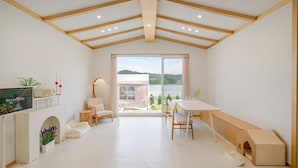 A modern, well-lit room with a large sliding glass door leading to a balcony with a view of the outdoors.