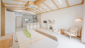 A modern living room with a dining area, a kitchen in the background, and a cozy seating arrangement.