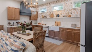 Eine moderne Küche mit Holzschränken, ein Essbereich mit Korbstühlen und einem eingebauten Backofen.