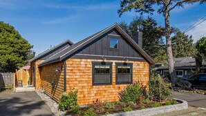 Eine moderne Blockhütte mit dunklem Dach, zwei Fenstern und einer kleinen Veranda.