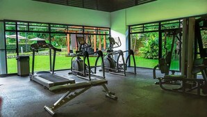 A gym with treadmills, elliptical machines, and weight equipment, large windows, and a view of greenery outside. - Macaw House with private pool in Arenas Herradura (Playa Herradura)