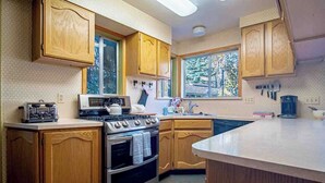 Une cuisine avec des meubles de rangement en bois, une cuisinière, un four à micro-ondes et un évier.