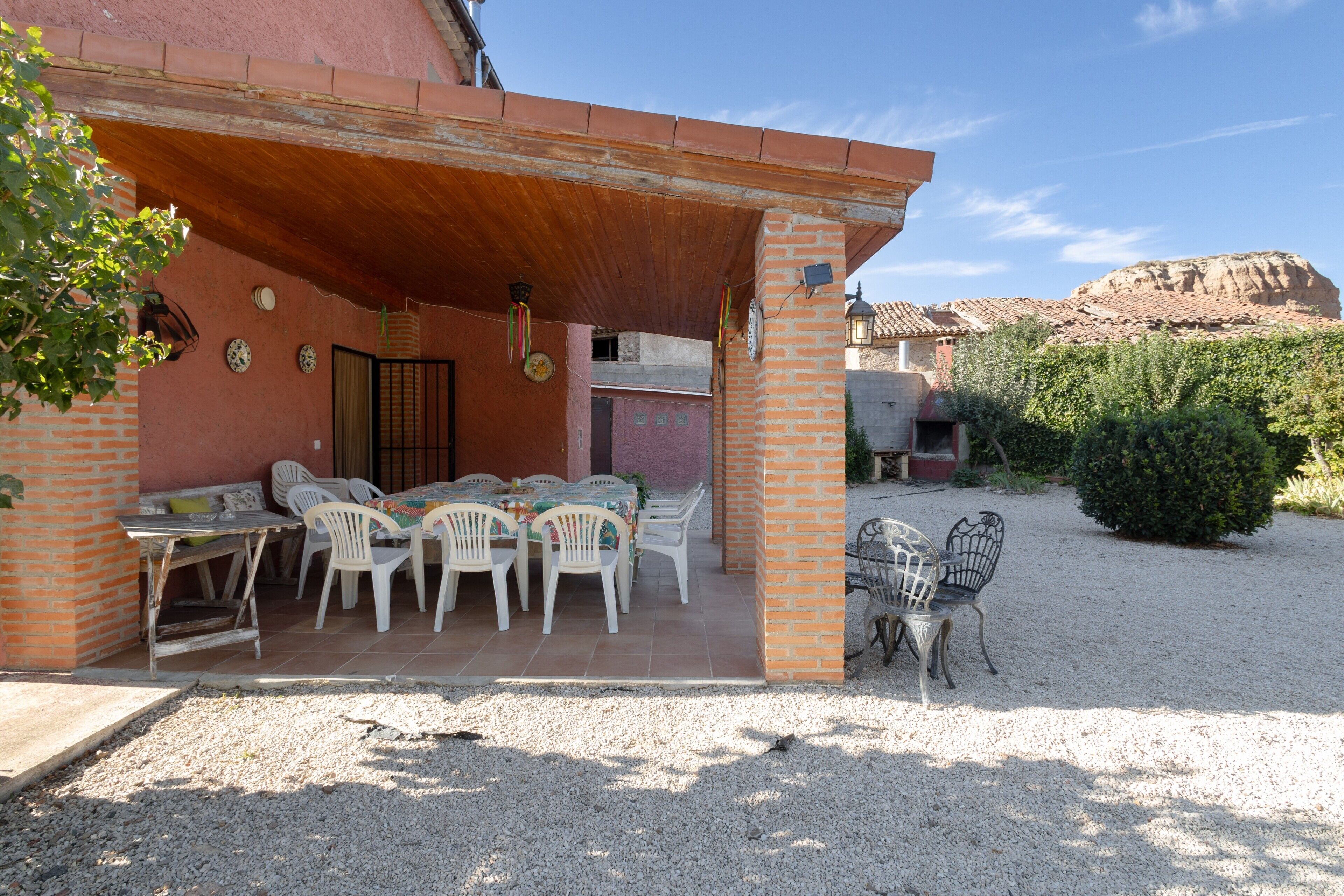 Um pátio com mesa e cadeiras, um muro de tijolos e vista para uma montanha.