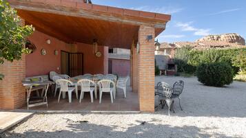 Um pátio com mesa e cadeiras, um muro de tijolos e vista para uma montanha.