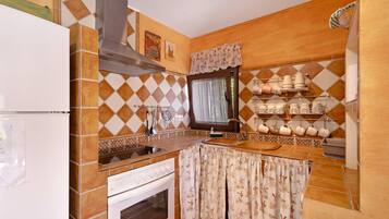A kitchen with a stove, oven, sink, and a window with curtains.