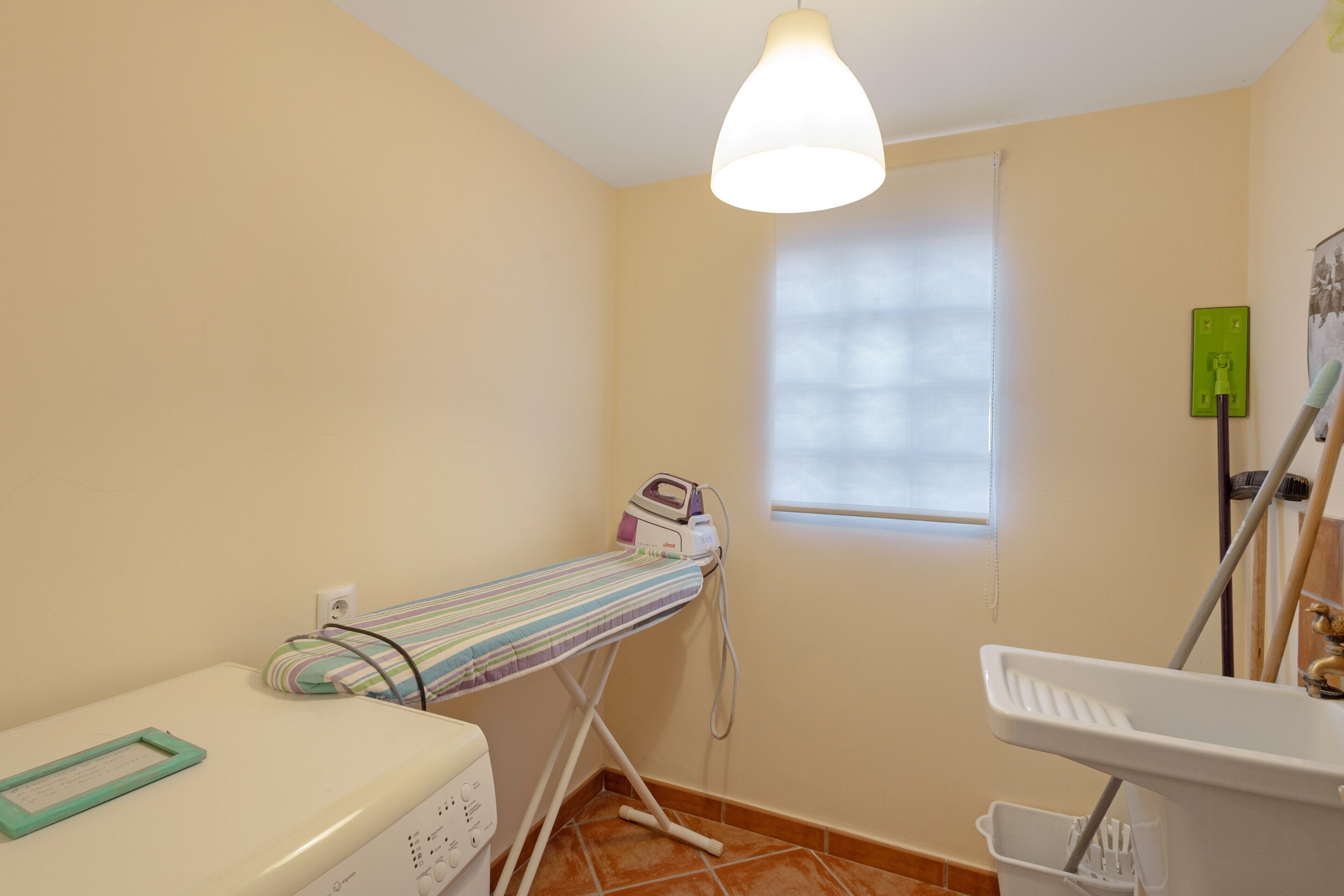 Una habitación pequeña y limpia con cama, ventana, lavabo y espejo.