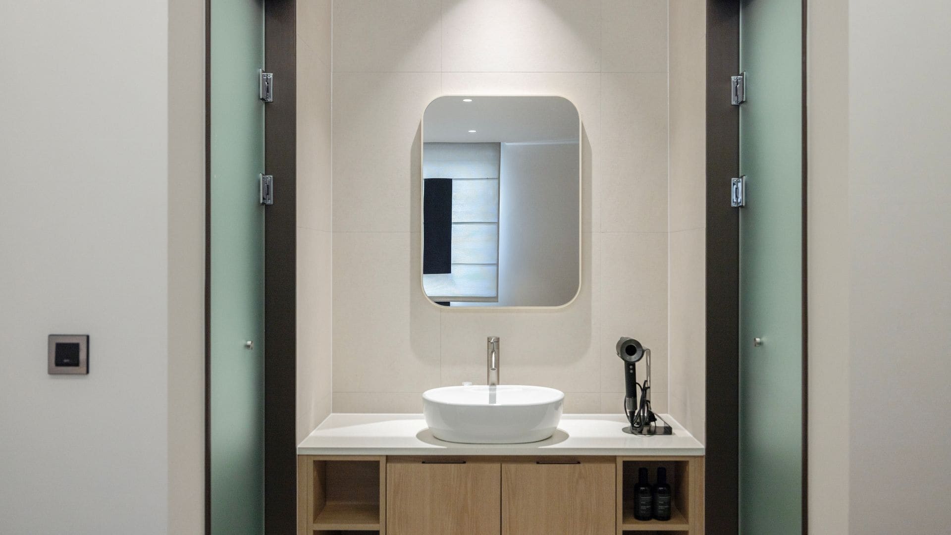 A modern bathroom with a white sink, a mirror, and a vanity with a light fixture.