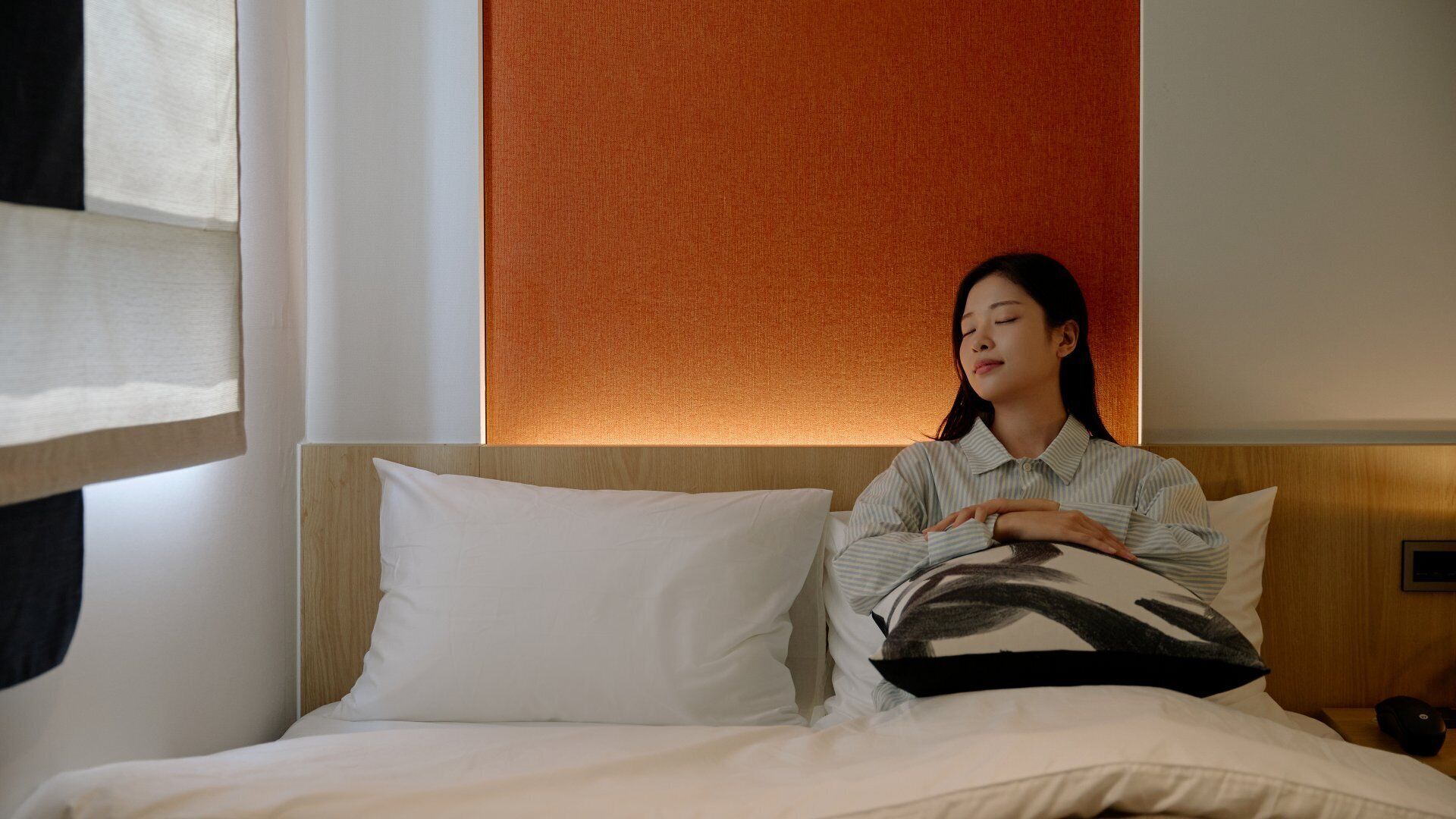 A hotel room with a bed, pillows, and a headboard.