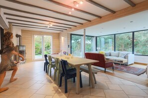 Un amplio salón con un gran ventanal, una chimenea y una mesa de comedor con sillas.