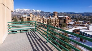 A balcony with a view of snow-covered mountains and a town below.