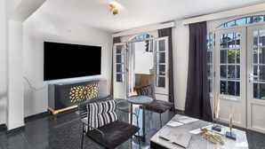A modern living room with a flat-screen TV, a glass coffee table, and a sofa with striped cushions.