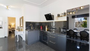 A modern kitchen with dark cabinetry, a marble backsplash, and a dining area with black chairs.