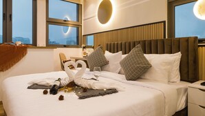 A hotel room with a large bed, a headboard, and a view of the city through large windows. - Riveria Premium Kuala Lumpur, Roam (Kuala Lumpur)
