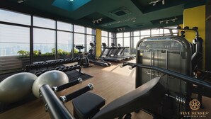 A gym with exercise equipment, large windows, and a view of the city. - Riveria Premium Kuala Lumpur, Roam (Kuala Lumpur)