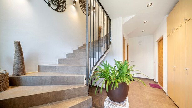 A staircase with a modern design, a potted plant, and a decorative wall piece. - Apartment 'Fuchsberger  A' with Mountain View, Wi-Fi and Air Conditioning (Lana)