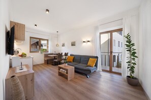 Een moderne woonkamer met een bank, salontafel en een eethoek met stoelen en een tafel.