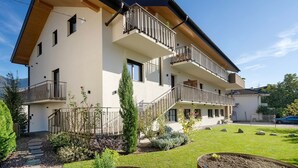 A multi-story building with balconies, a garden, and a clear sky. - Apartment 'Fuchsberger  A' with Mountain View, Wi-Fi and Air Conditioning (Lana)