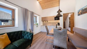 Ein moderner Wohnraum mit Sofa, Esstisch und Küchenzeile.