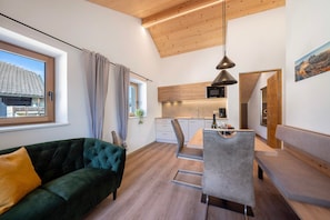 Un espacio habitable moderno con sofá, mesa de comedor y zona de cocina.