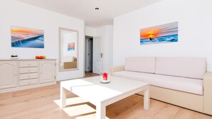 A modern living room with a white sofa, a coffee table, and two paintings on the wall.