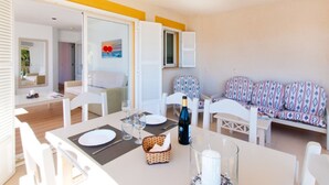 A dining area with a table set for two, a sofa, and a view of the outside.