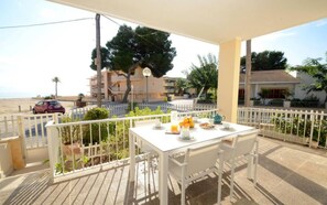 Un balcon avec une table dressée pour le petit-déjeuner, donnant sur une plage et des immeubles d’habitation.