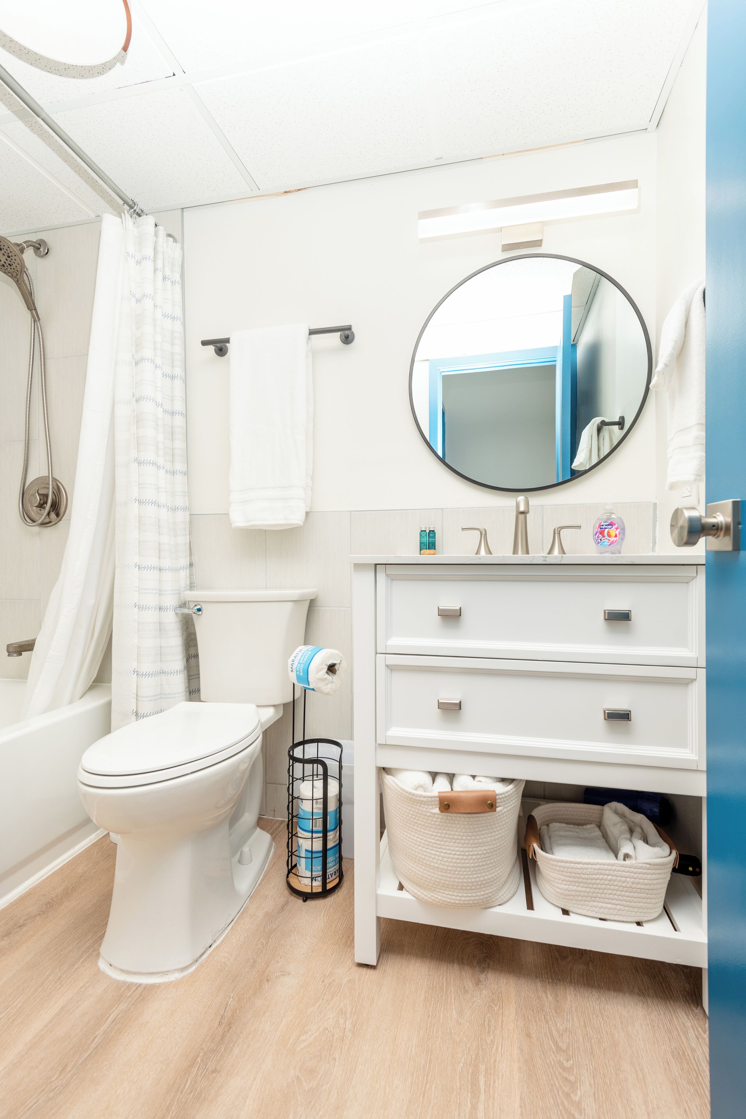 A modern bathroom with a toilet, sink, and shower. There are towels and toiletries on the counter.