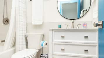 A modern bathroom with a toilet, sink, and shower. There are towels and toiletries on the counter.